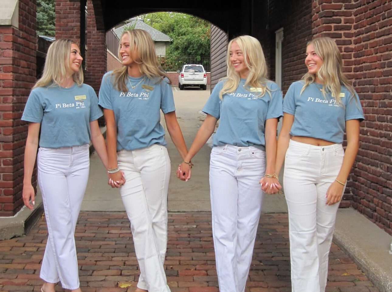 Four members wearing matching blue shirts and white pants holding hands