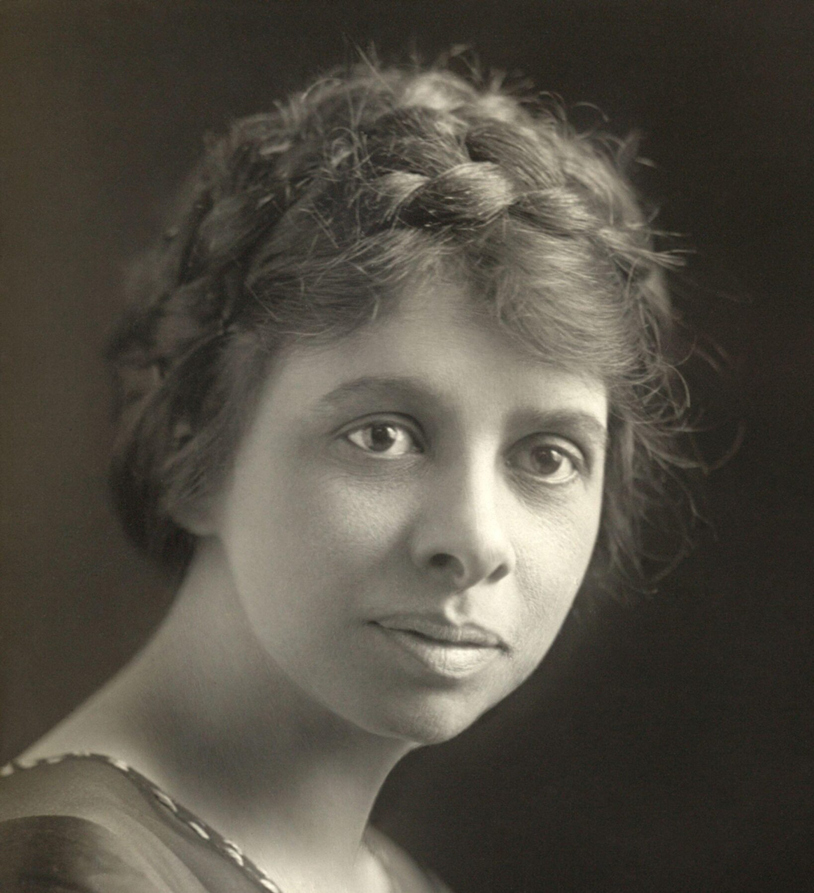 Historical sepia-toned headshot of Iris Calderhead with braids in her hair in front of a black background