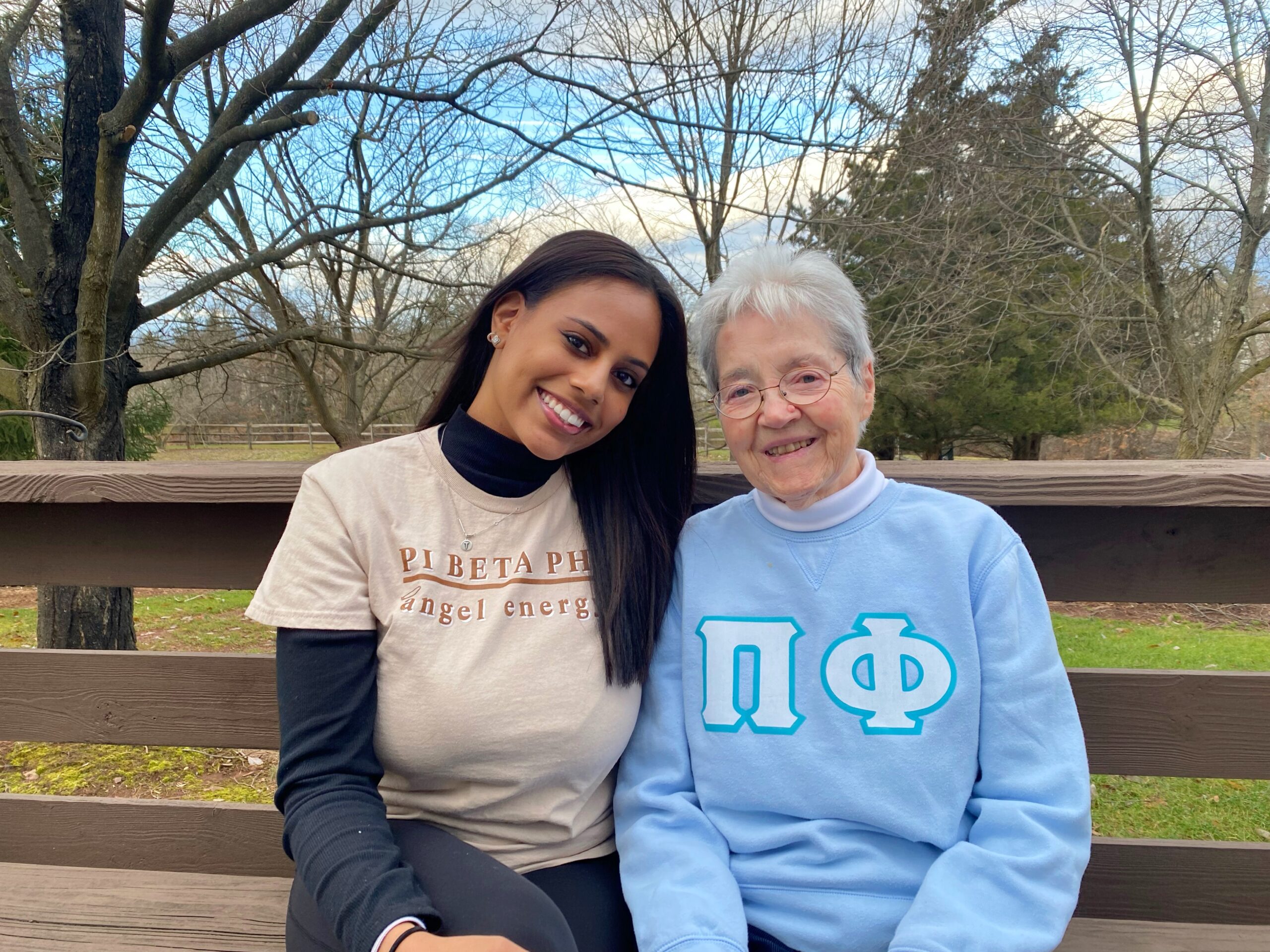 An older member and a younger member sitting on a bench outdoors
