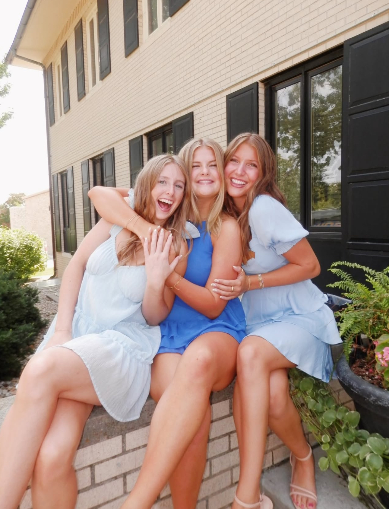Three members hugging one another while sitting in front of the chapter house