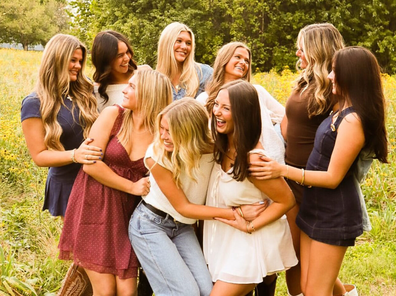 Nine members standing in front of a tree