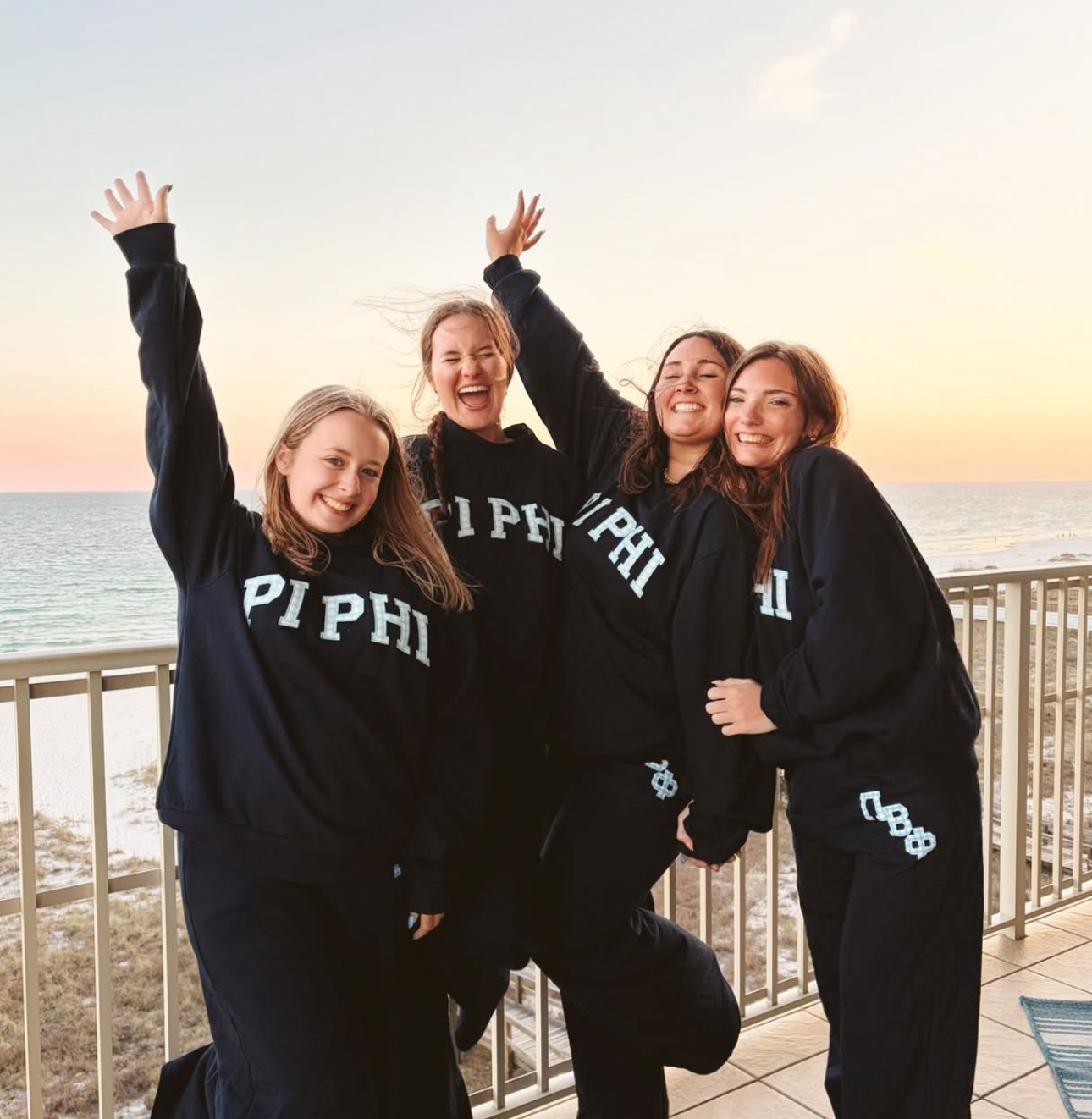 Four individuals standing outdoors wearing Pi Phi sweatsuits