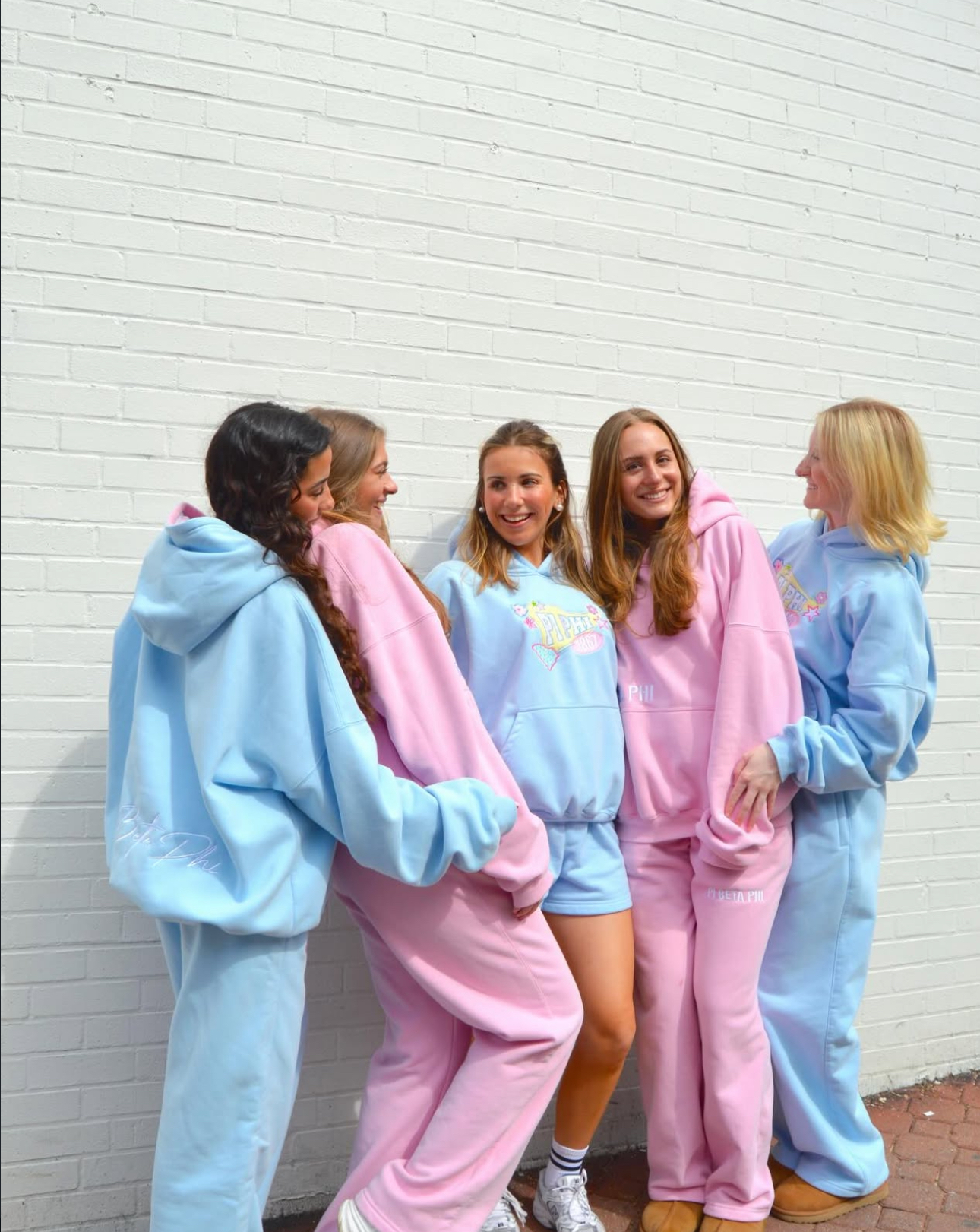 Five members standing outdoors wearing Pi Phi sweatsuits