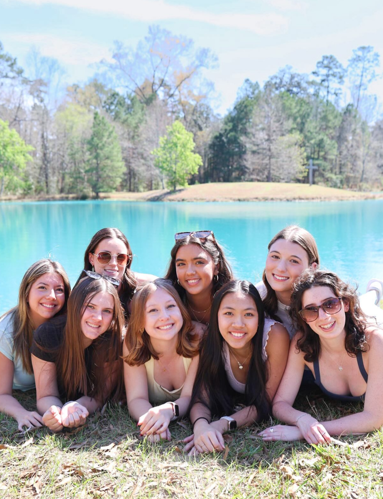 Eight members lying down outside in front of a lake