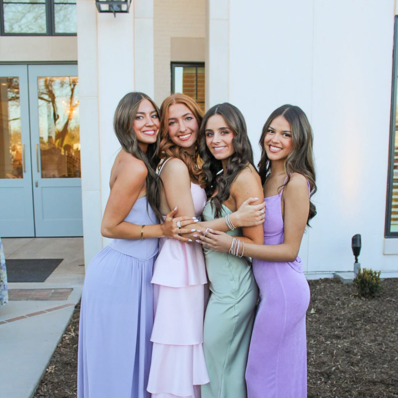 Four members wearing dresses hugging