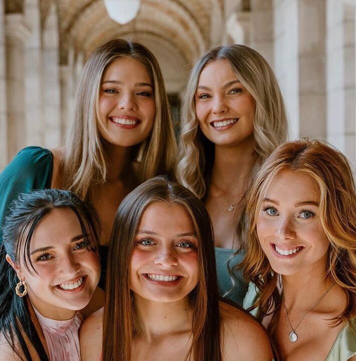 Five members smiling in front of stone archway