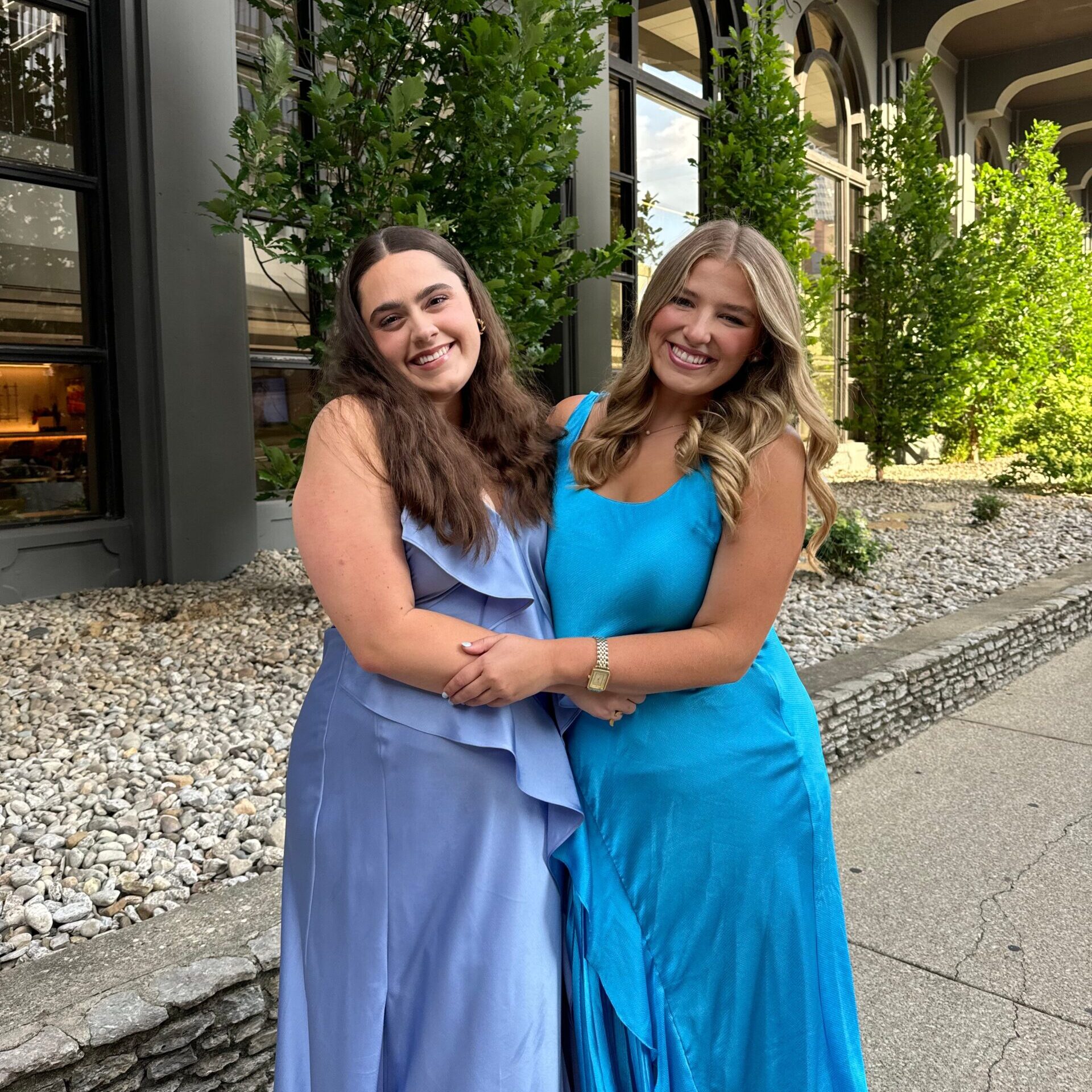 Two members wearing blue dresses under an overpass