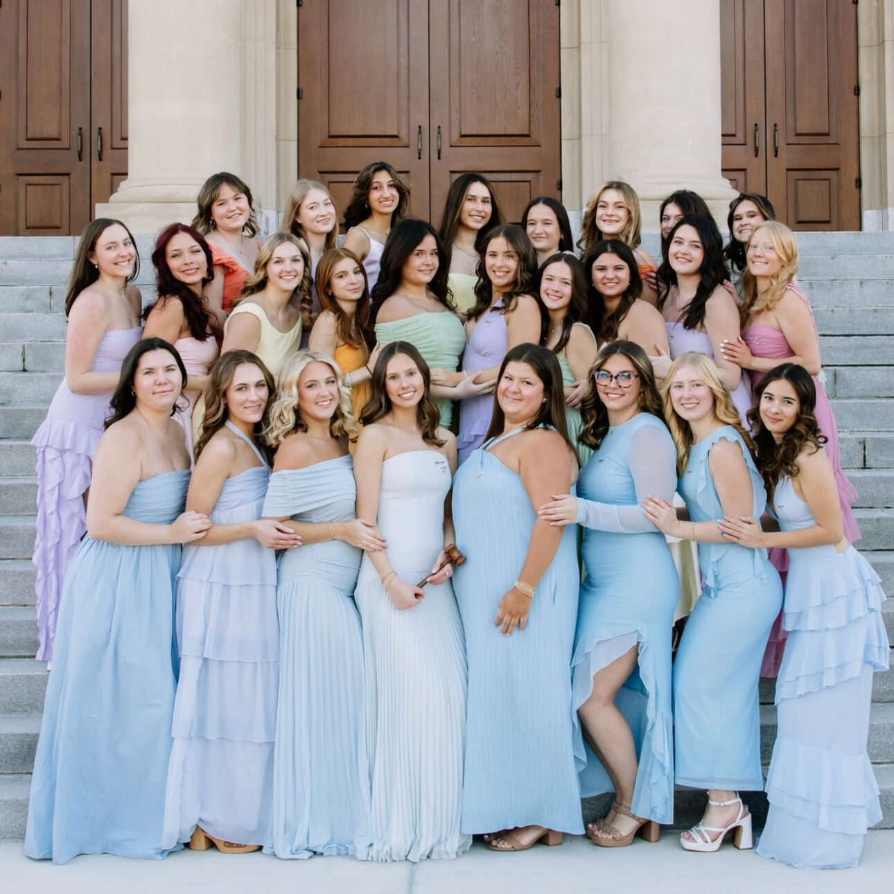 Several members wearing long dresses standing on the steps of a building