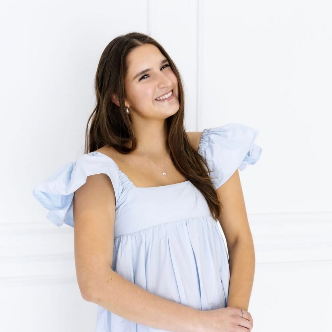 Professional headshot of Caitlyn Bradley wearing a silver blue dress
