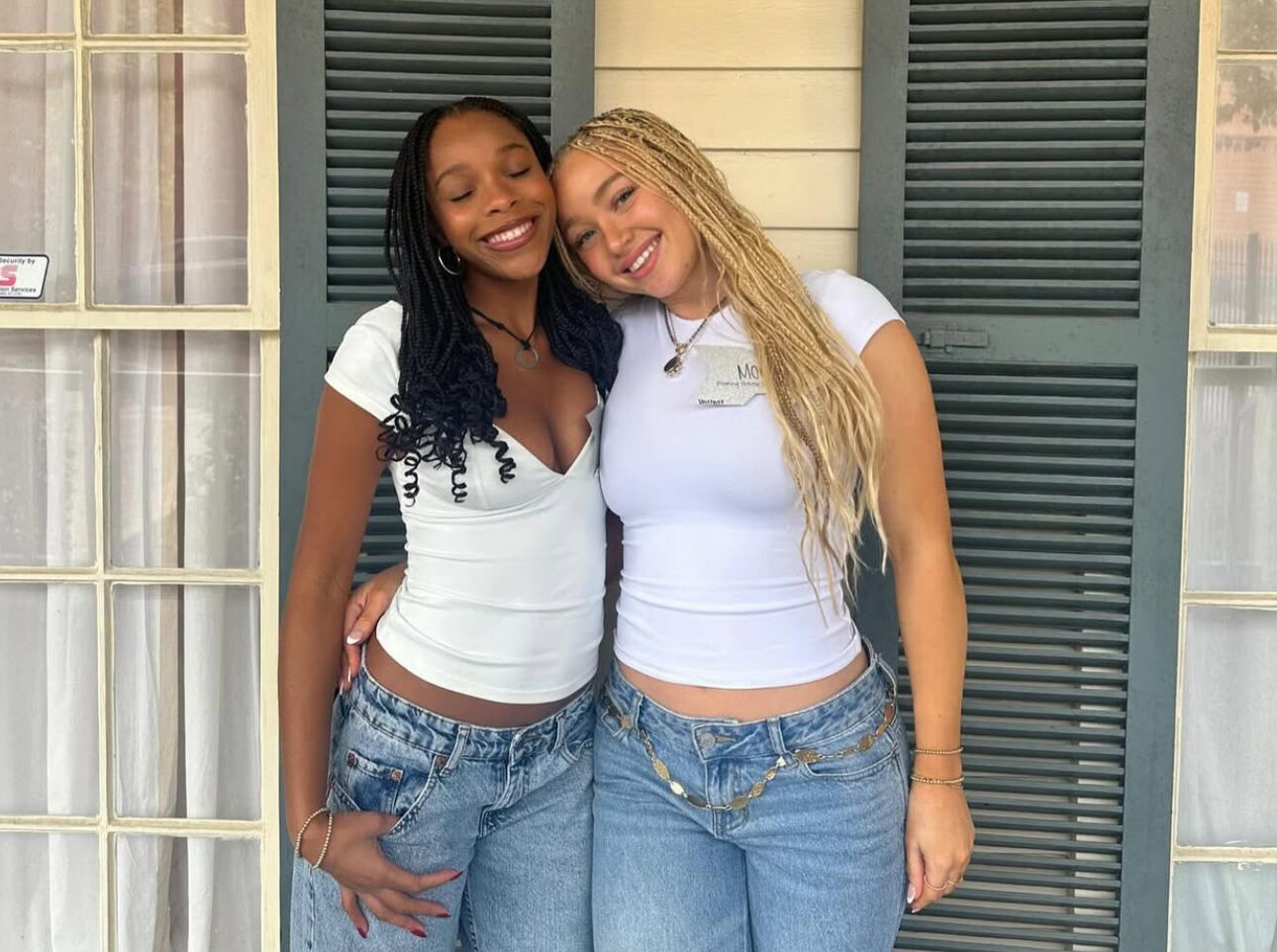 Two members standing on front of a window