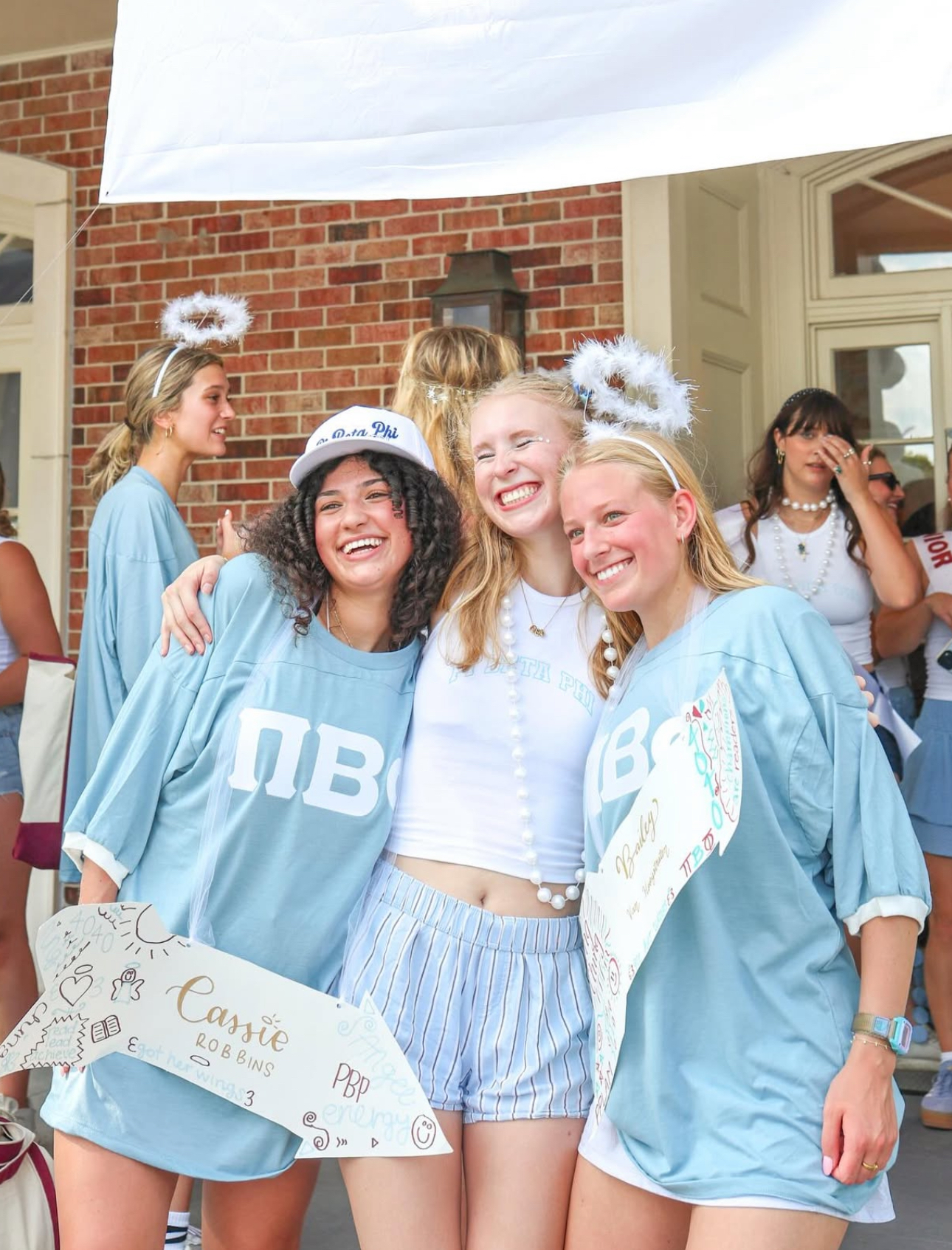 Three individuals standing outdoors wearing Pi Phi shirts on Bid Day