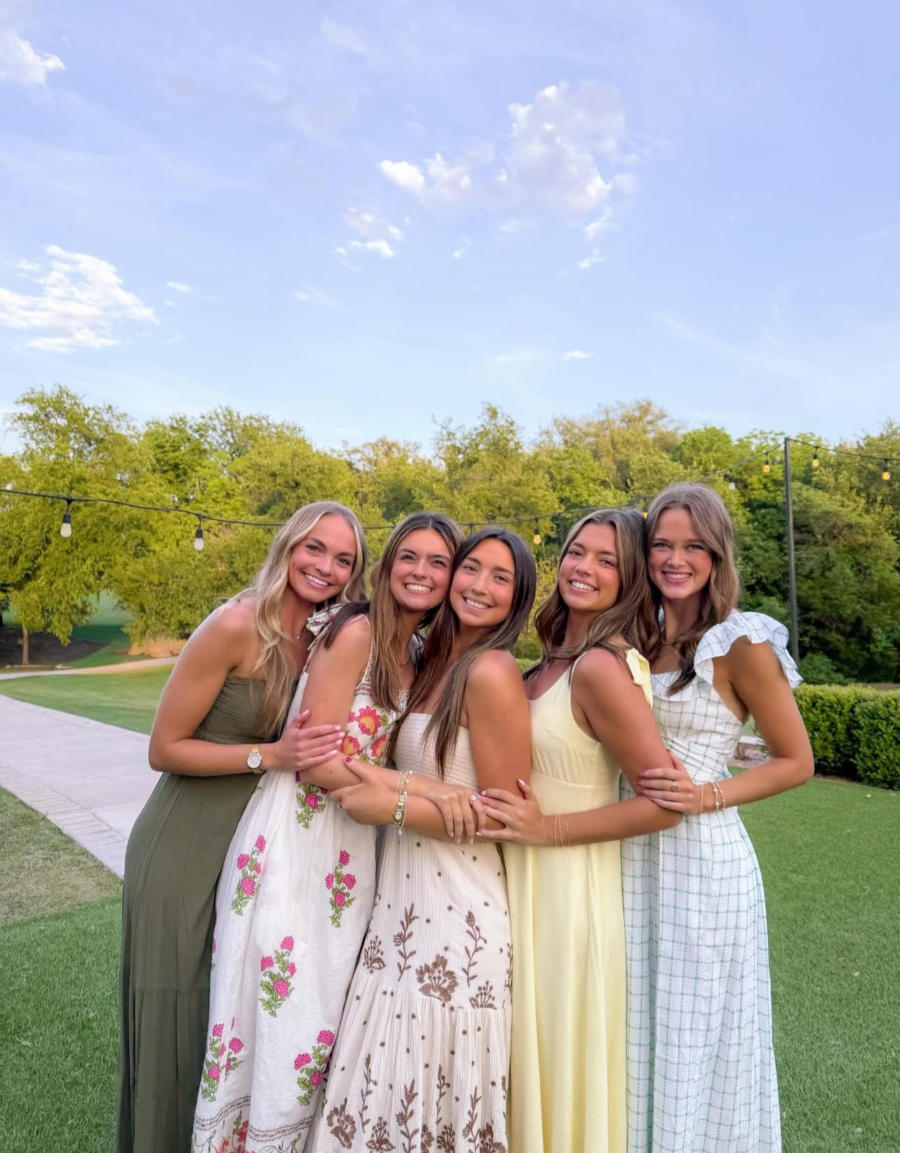 Five individuals standing outdoors hugging