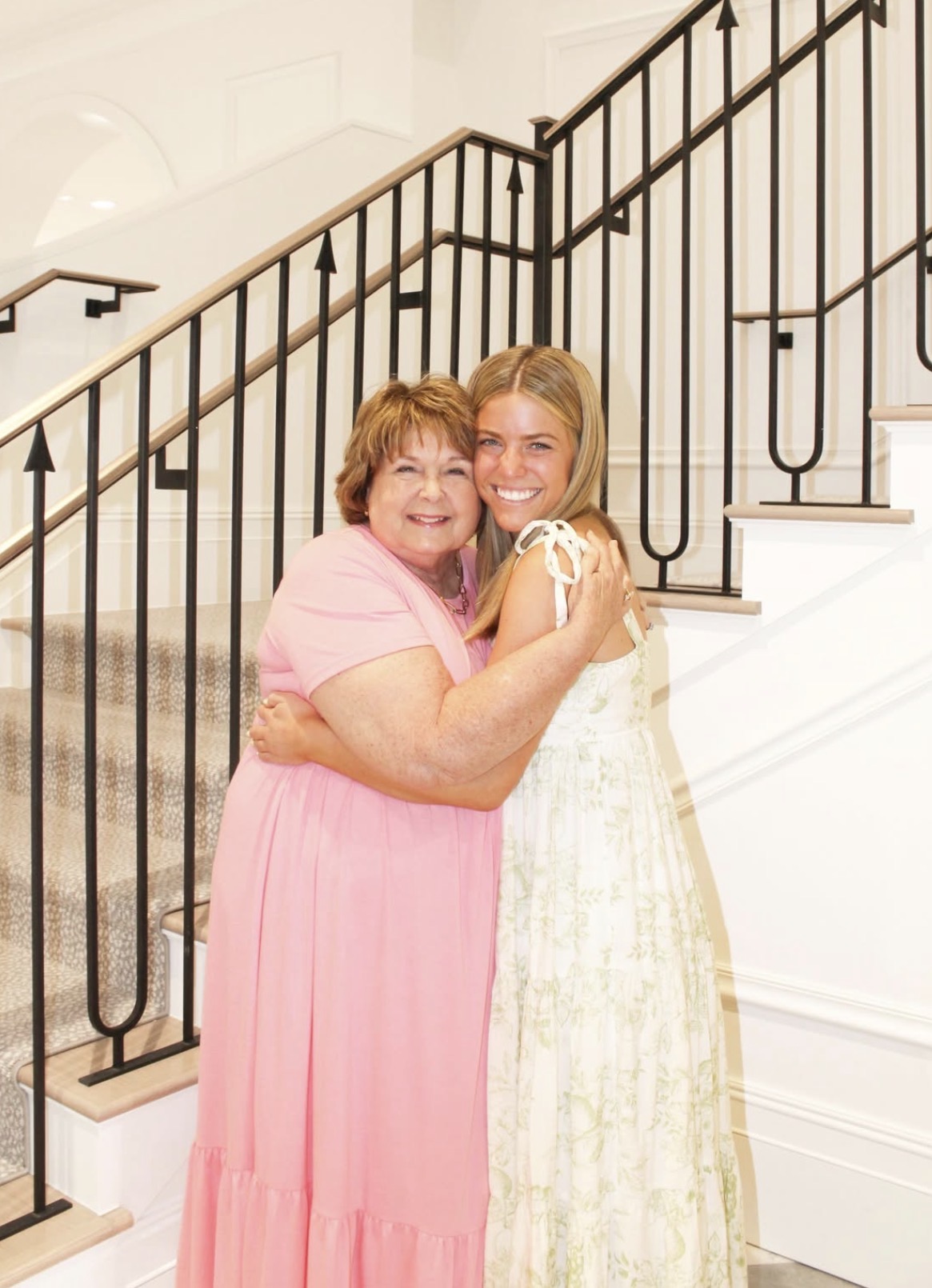 An older member and younger member hugging in front of a staircase