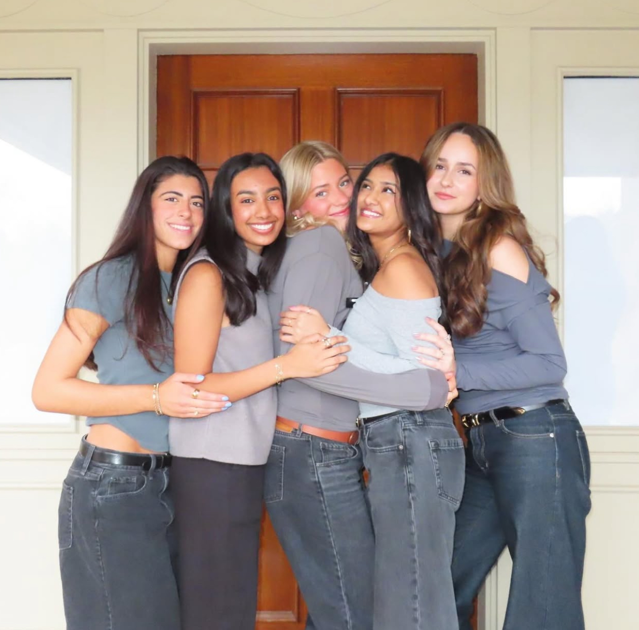 Five members standing outside wearing black pants and gray shirts