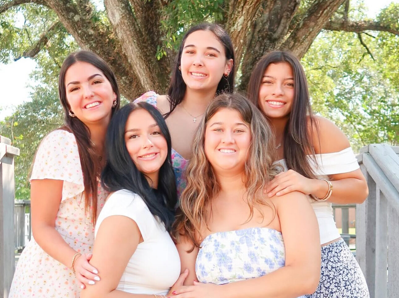 Five members standing in front of a tree