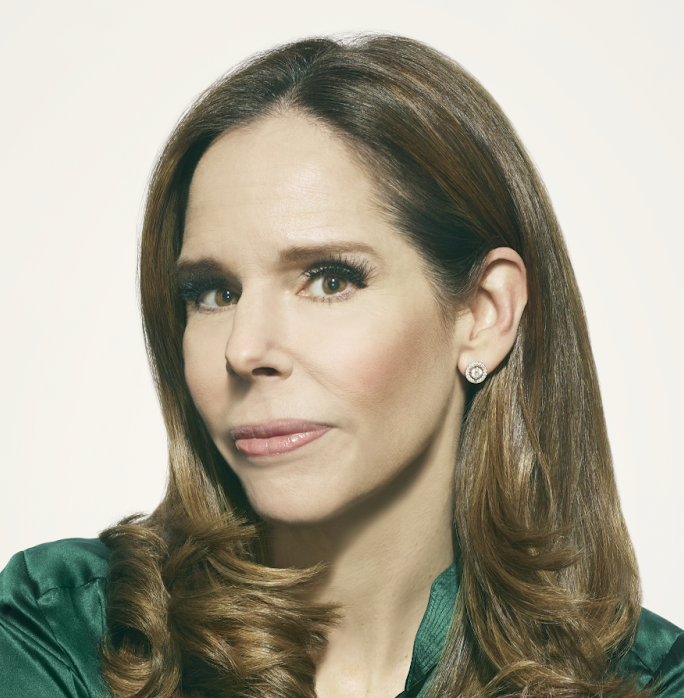 Professional headshot of Moira Forbes wearing a green shirt in front of a beige background