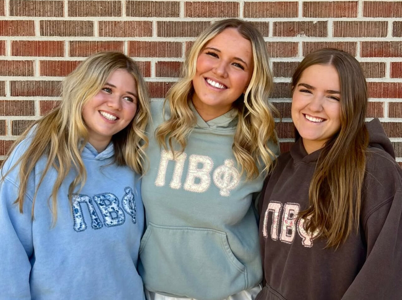 Three members wearing hoodies with the Pi Beta Phi Greek letters