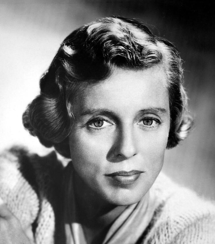 Historical black and white headshot of Nancy Kulp wearing a light colored blouse and scarf in front of a grey background