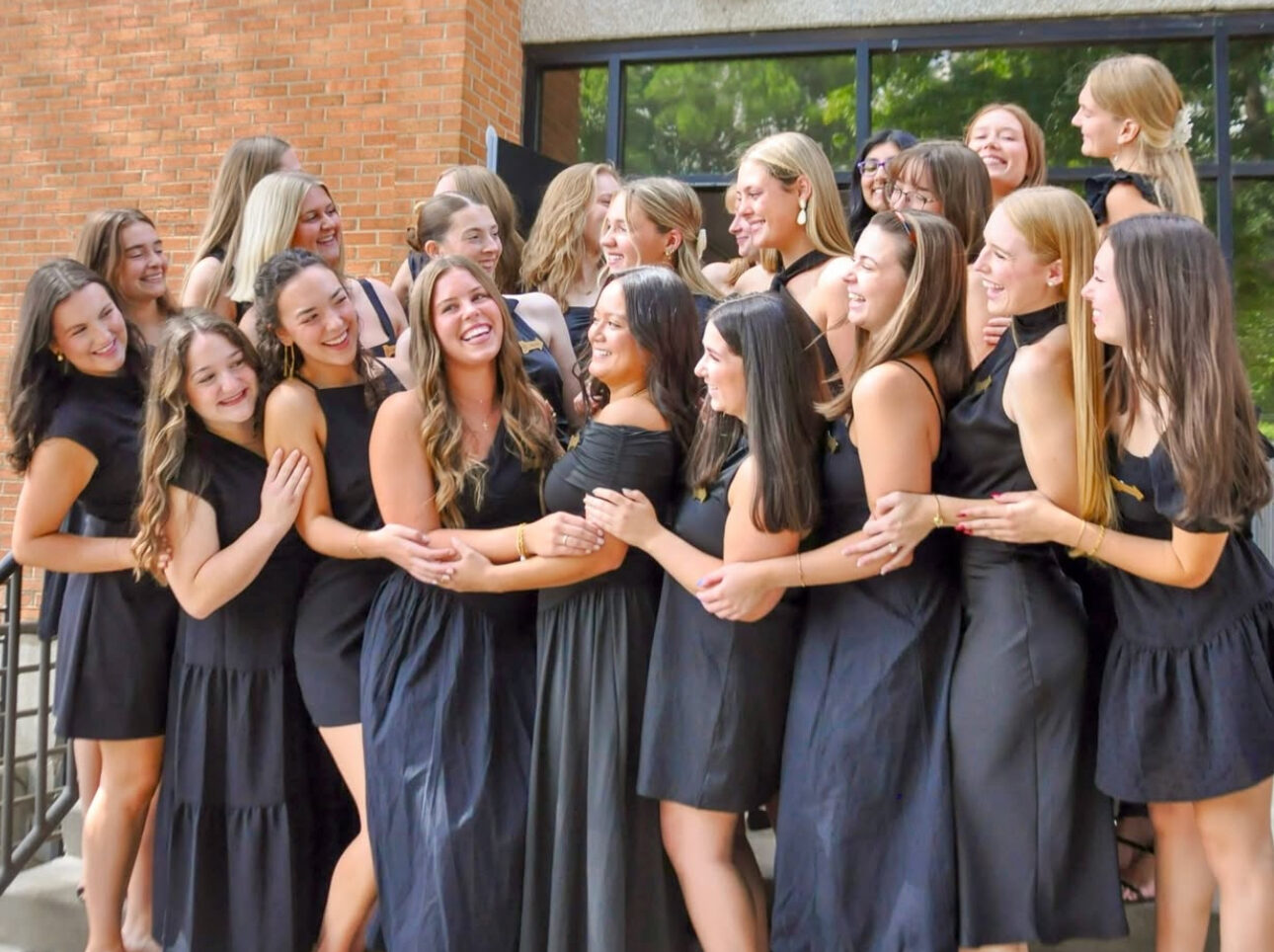 Several members wearing black standing in front of the chapter house