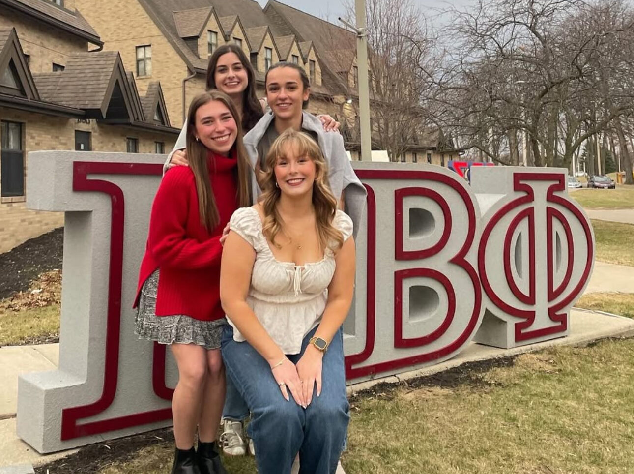 Four members standing in front of giant Pi Beta Phi Greek letters