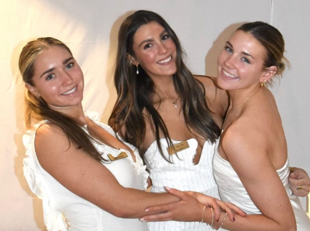 Three members wearing white and hugging