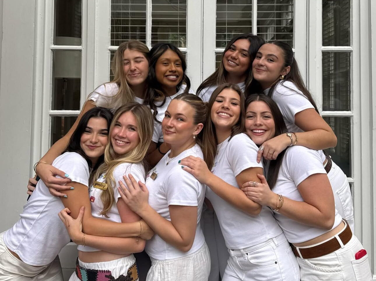 Several members wearing all white standing in front of a window