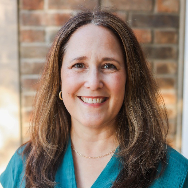 Professional headshot of Becky Bottorf wearing a teal blouse in front of a brick wall