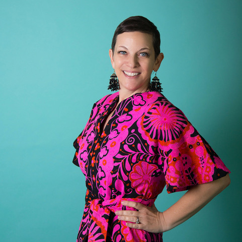 Professional headshot of Melanie Dillman wearing a pink and black patterned dress