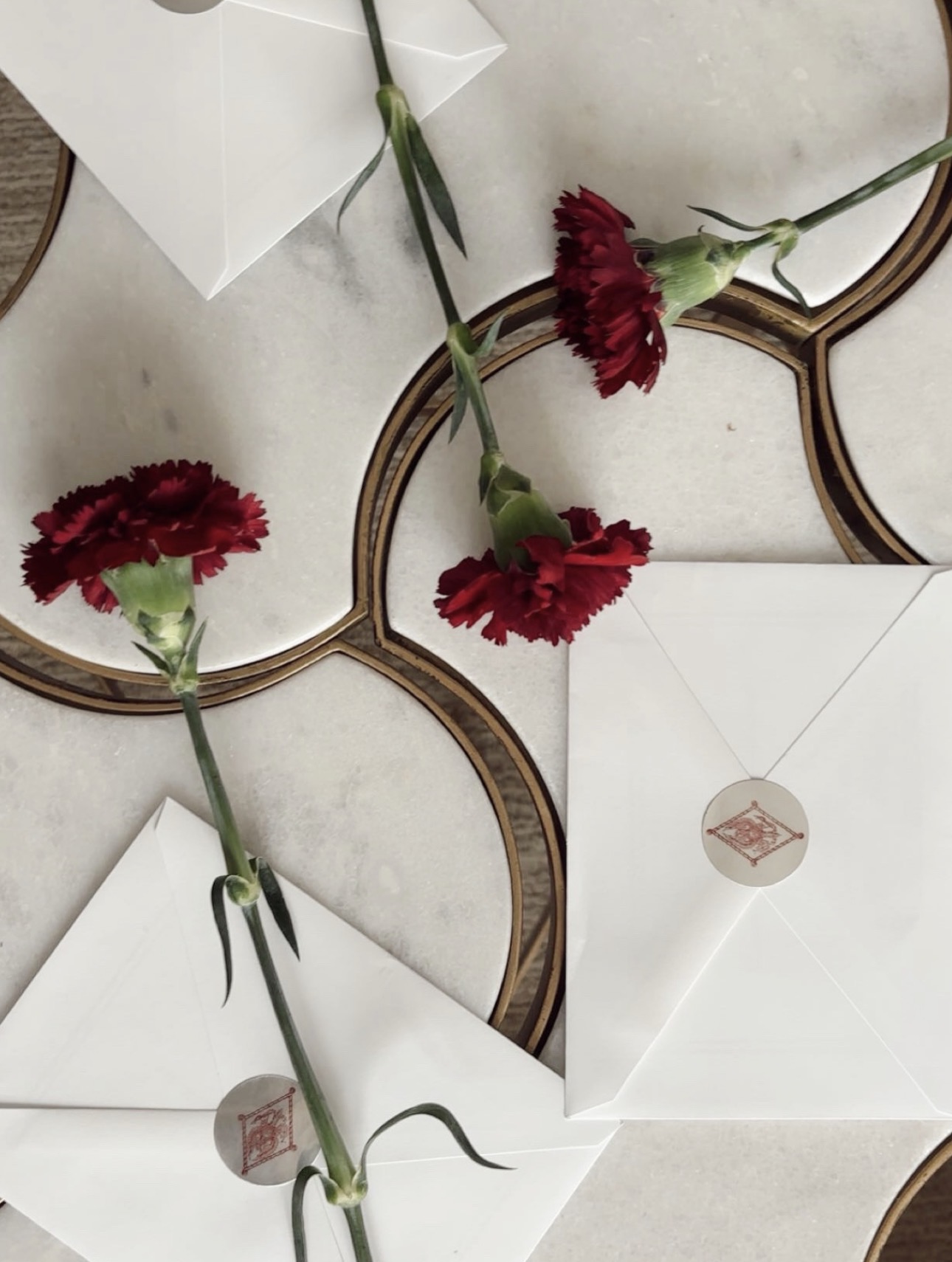 Three wine carnations lying on a table with envelopes