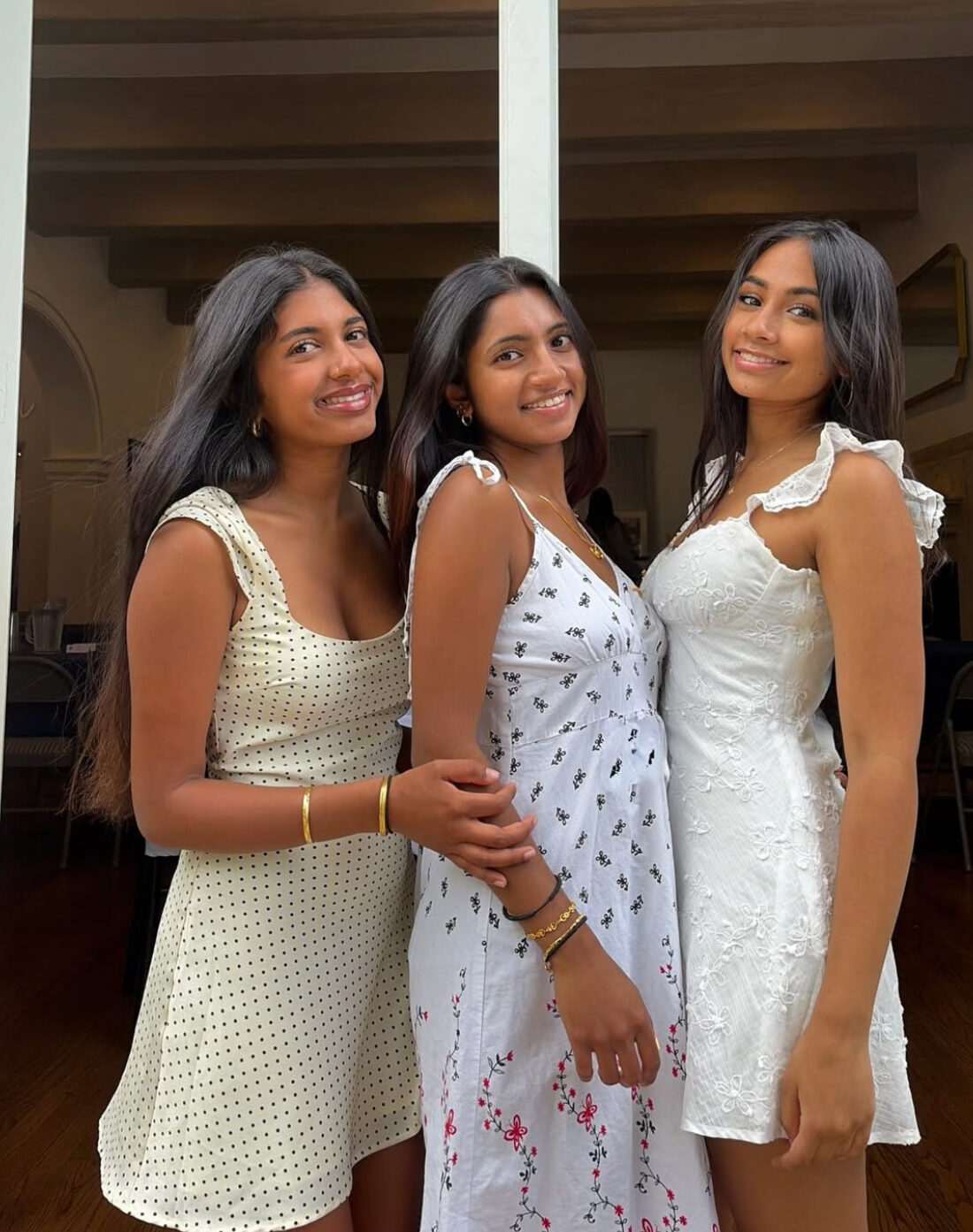 Three members wearing white dresses standing outside