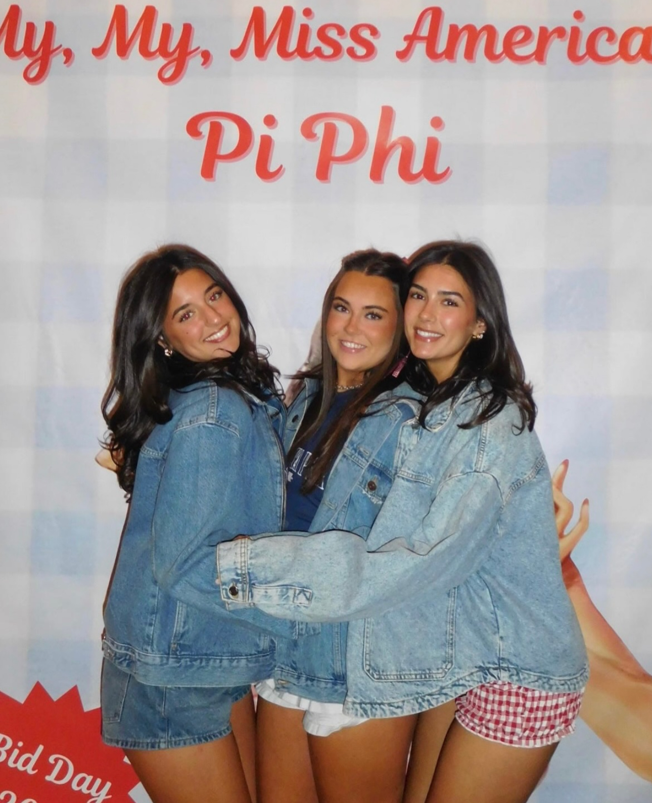 Three members standing in front of a banner that says My, My Miss American Pi Phi