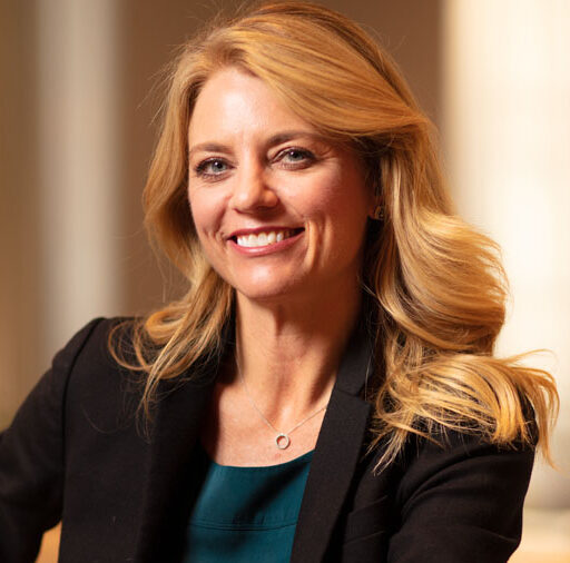 Professional headshot of Renie Anderson wearing a black blazer in front of a light blurred background