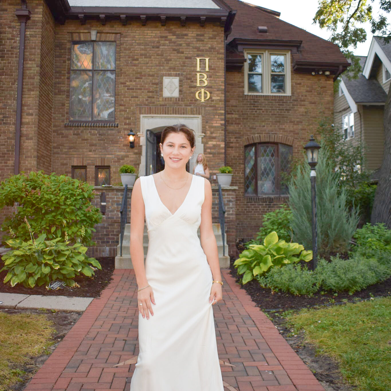 Photo of Bella Dols standing in front of a chapter house wearing a white dress