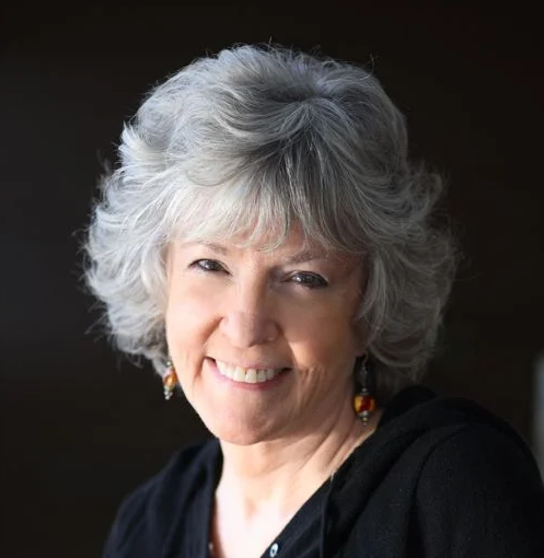 Professional headshot of Sue Grafton wearing a black shirt in front of a black background