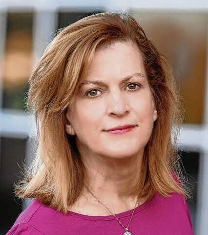 Professional headshot of Susan Chase Lottich wearing a pink shirt outdoors in front a window