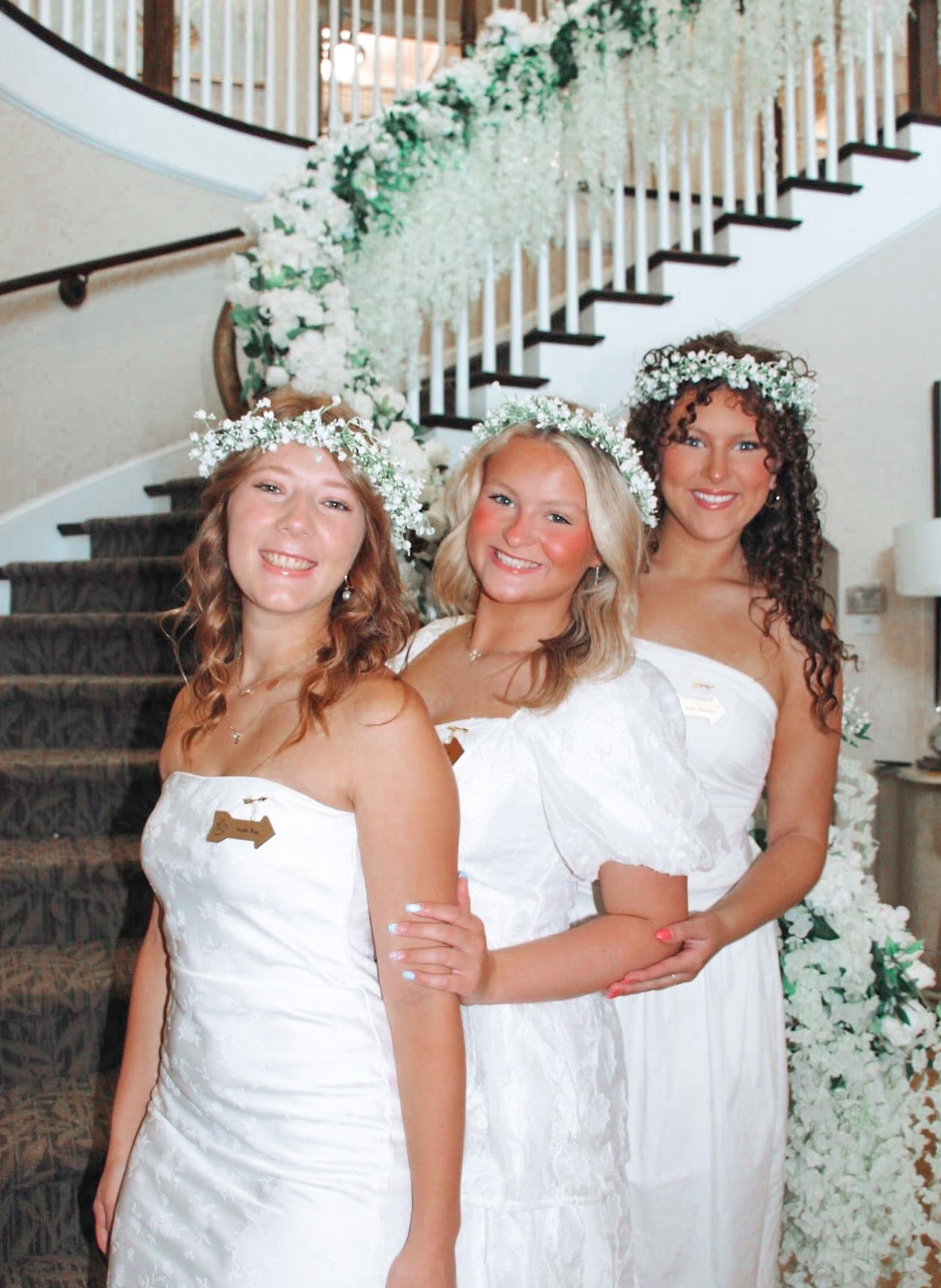 Three members wearing white standing in front of a staircase