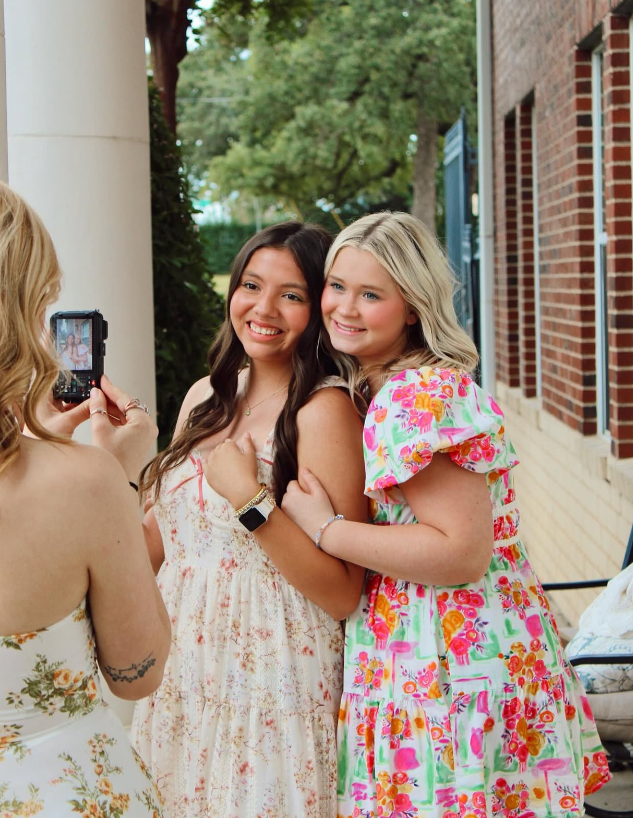 Two members pose for a photo and another member takes the photo with a digital camera
