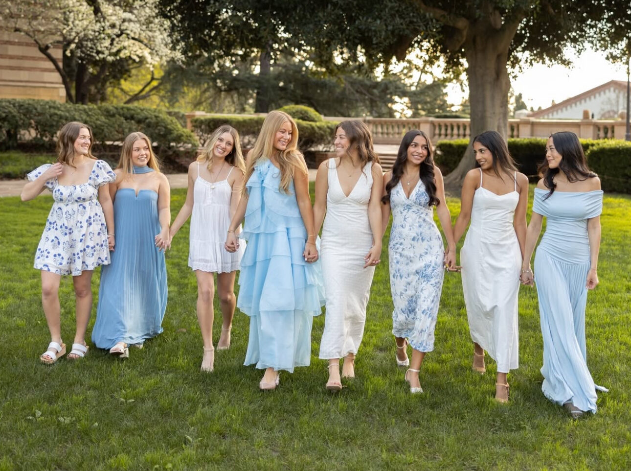 Eight members walking outdoors wearing blue dresses
