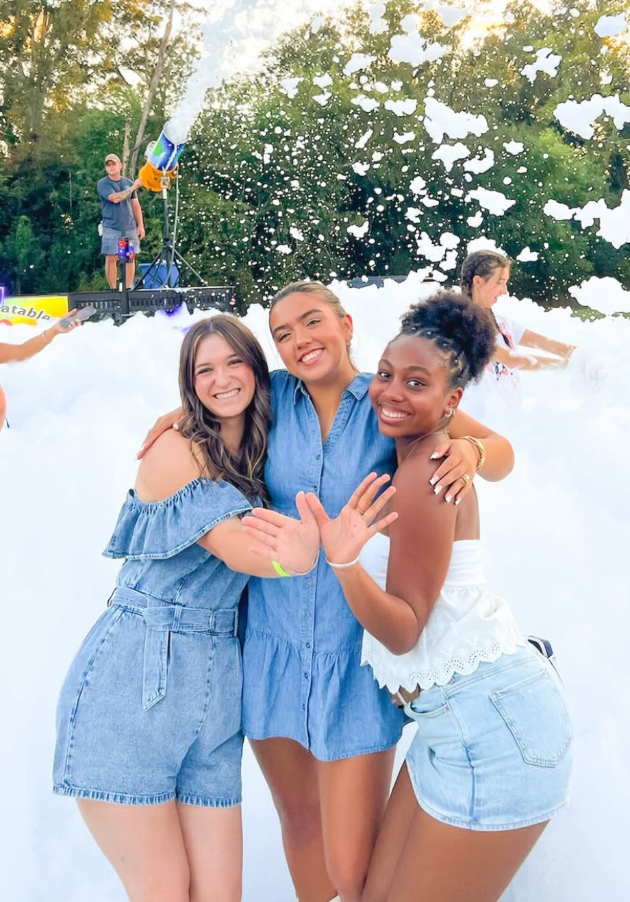 Three individuals standing outdoors making angel wings with their hands