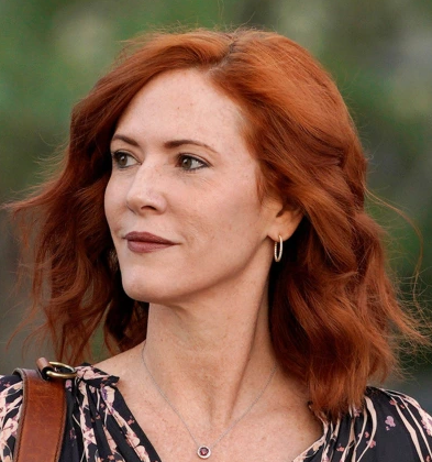 Headshot of Tree Paine looking to her left wearing a black and white shirt in front of a blurred backgrounf