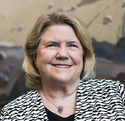 Professional headshot of Valerie Neal in a black and white jacket in front of a beige background