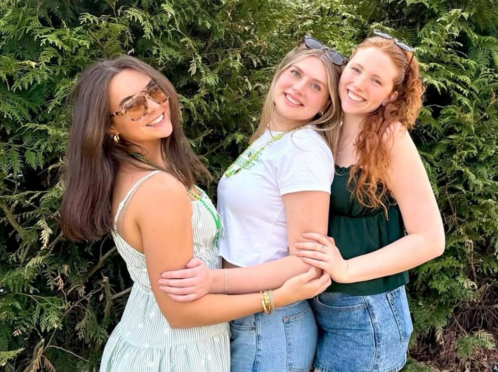 Three members standing in front of trees