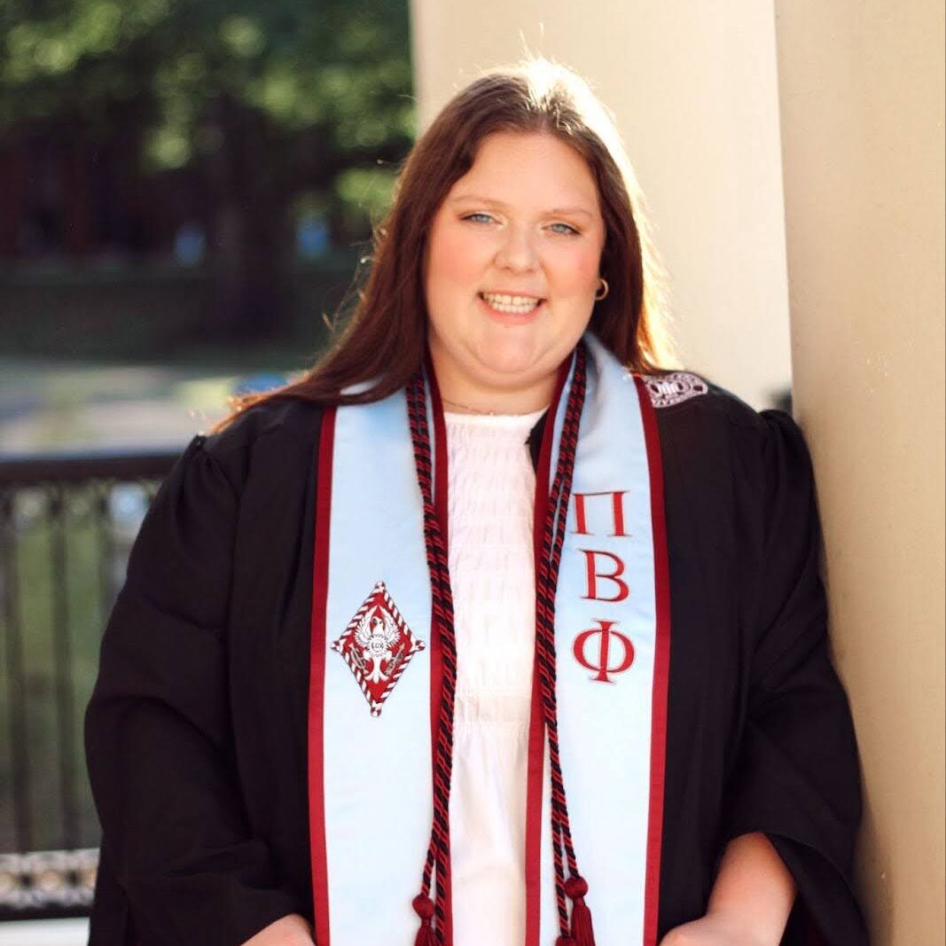 Photo of Meg Gordon wearing a graduation robe and Pi Beta Phi graduation stole