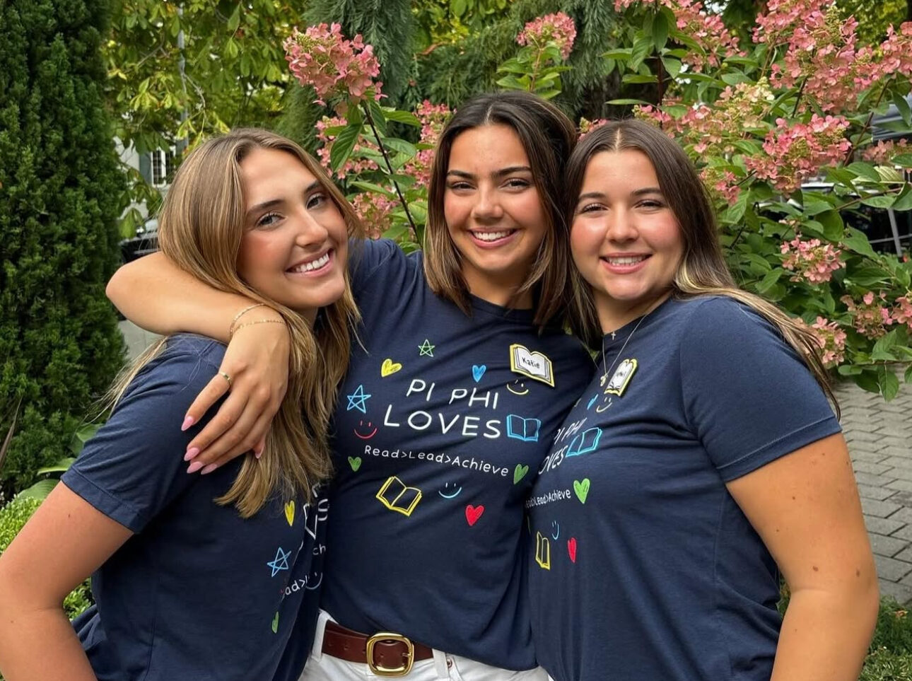 Three members smiling in front of trees