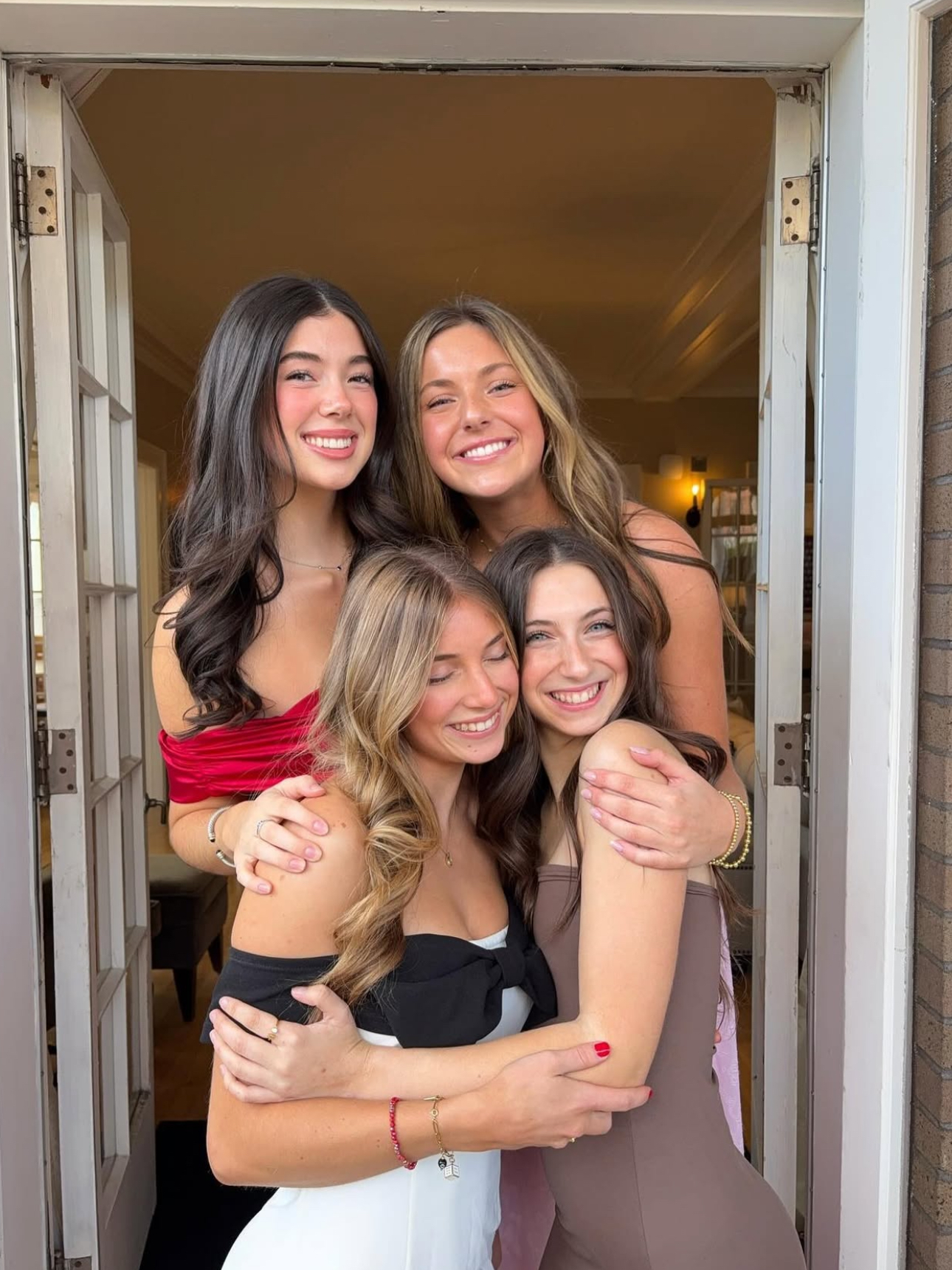Four members hugging each other in a doorway