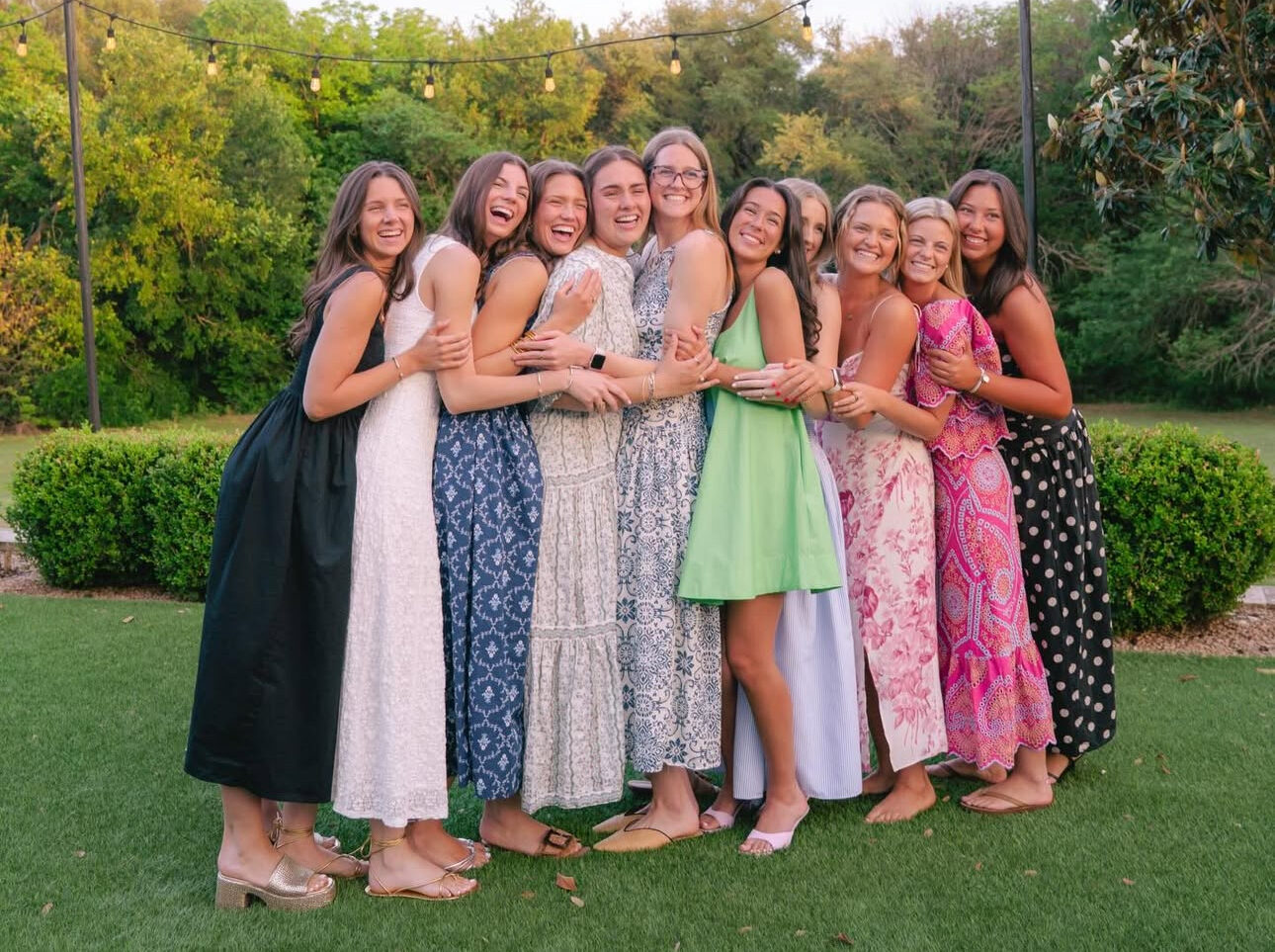 Ten individuals standing outdoors hugging