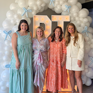 Four alumnae advisors in front of a balloon arch