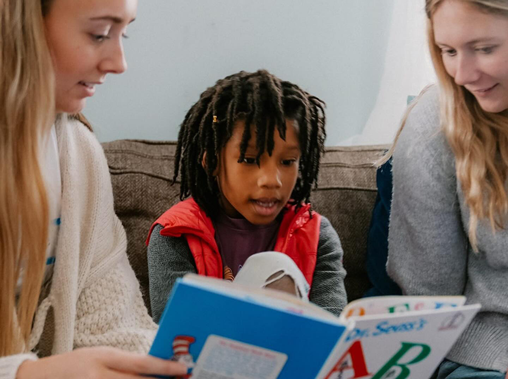 Two members reading a Dr. Seuss book to a child