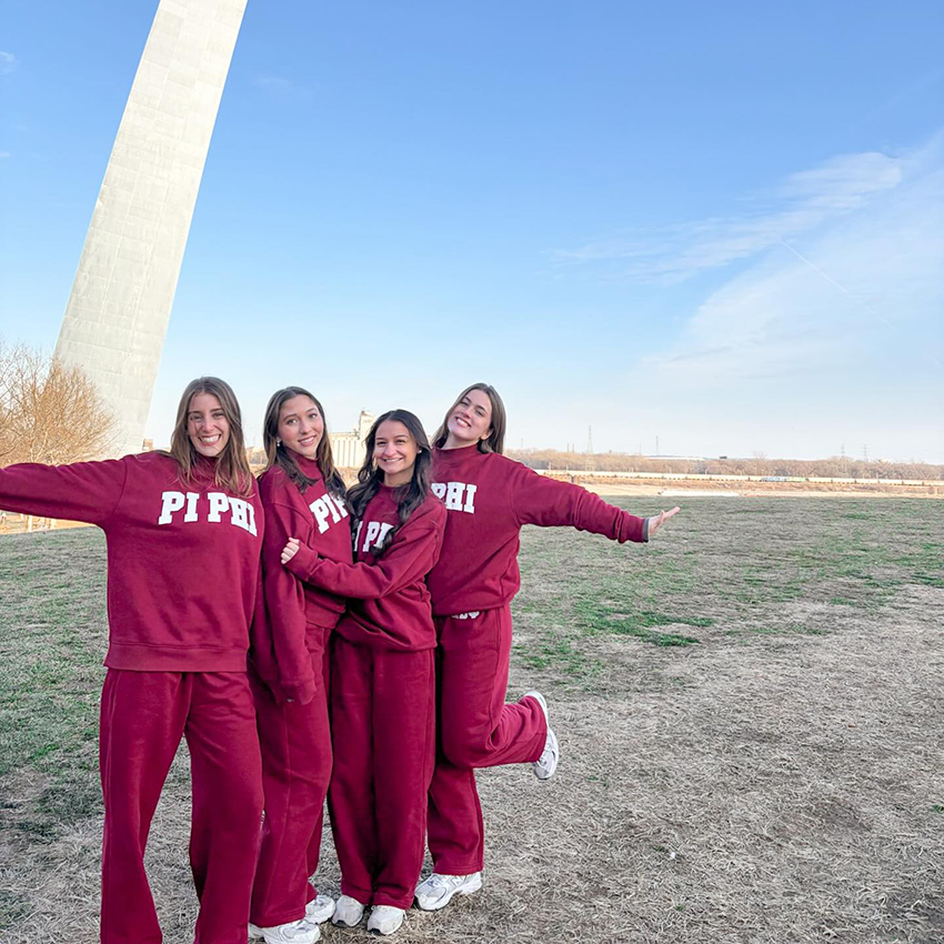 Four members wearing matching wine jumpsuits standing outdoors